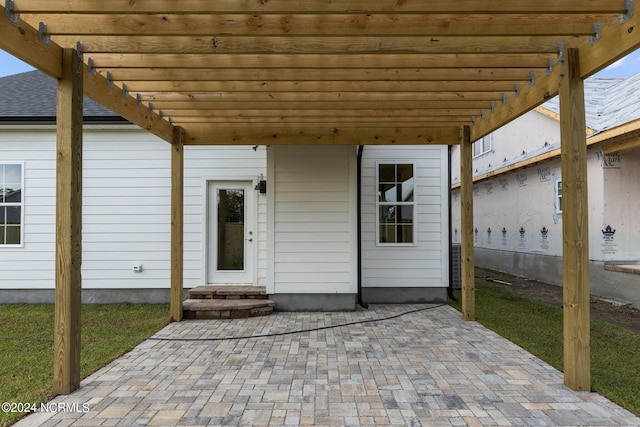 view of exterior entry featuring a pergola and a patio area