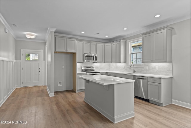 kitchen featuring light hardwood / wood-style floors, a wealth of natural light, ornamental molding, a kitchen island, and stainless steel appliances