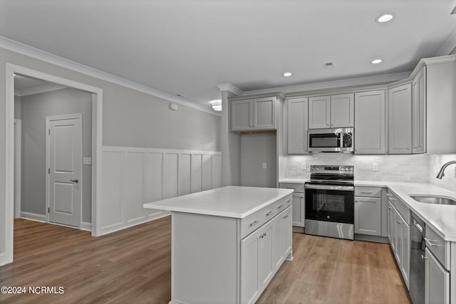 kitchen with ornamental molding, light hardwood / wood-style flooring, stainless steel appliances, sink, and tasteful backsplash