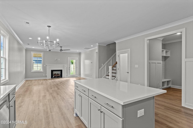 kitchen featuring an inviting chandelier, light hardwood / wood-style floors, hanging light fixtures, a center island, and ornamental molding