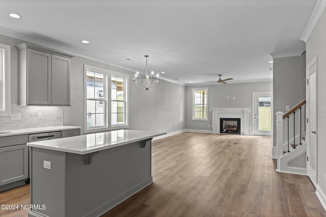 kitchen with a kitchen island, hanging light fixtures, tasteful backsplash, ornamental molding, and dark wood-type flooring