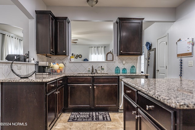 kitchen with backsplash, dark brown cabinets, light stone counters, and plenty of natural light