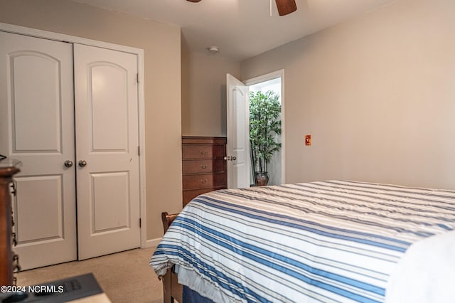 bedroom with ceiling fan, light colored carpet, and a closet