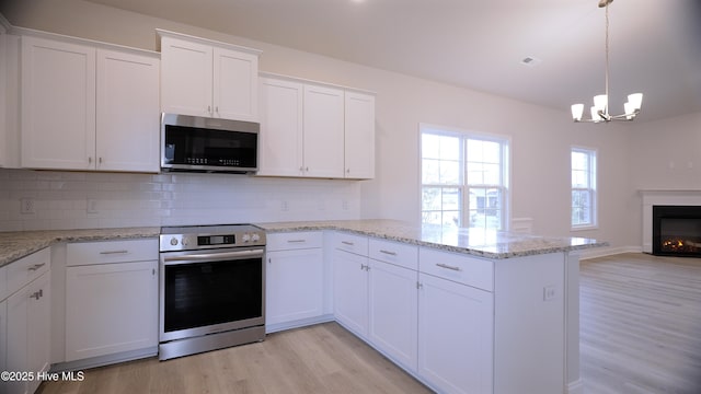 1254 Opaca Dr SE, Bolivia, NC 28422 - kitchen featuring stainless steel appliances, a peninsula, light wood-style flooring, a chandelier, and white cabinetry