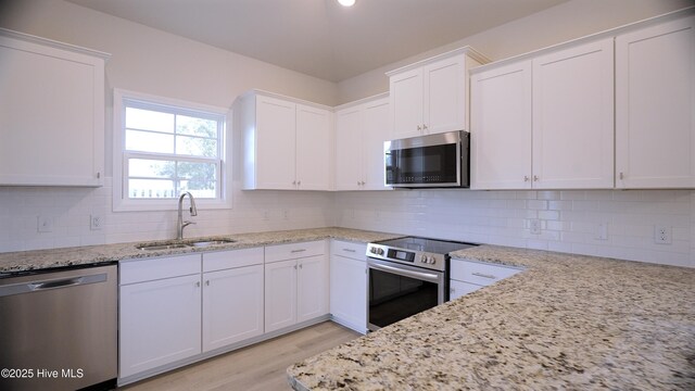 1254 Opaca Dr SE, Bolivia, NC 28422 - kitchen with stainless steel appliances, white cabinetry, light wood-type flooring, and light stone countertops