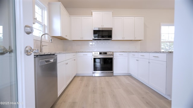 1254 Opaca Dr SE, Bolivia, NC 28422 - kitchen featuring stainless steel appliances, light stone countertops, tasteful backsplash, light wood-style floors, and white cabinets