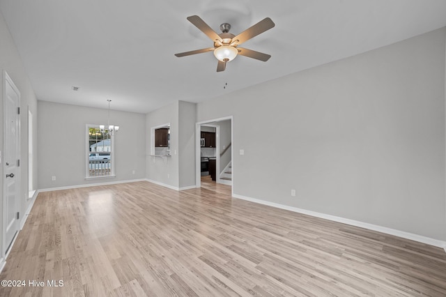 unfurnished living room featuring ceiling fan with notable chandelier and light hardwood / wood-style flooring