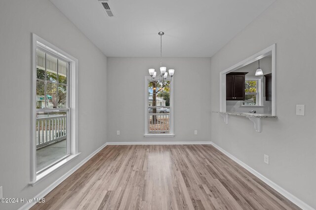 unfurnished dining area featuring light hardwood / wood-style floors and a chandelier