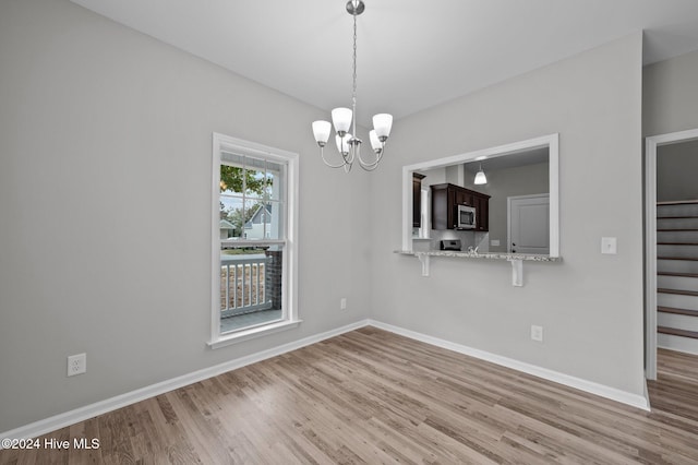 unfurnished dining area with light wood-type flooring and an inviting chandelier