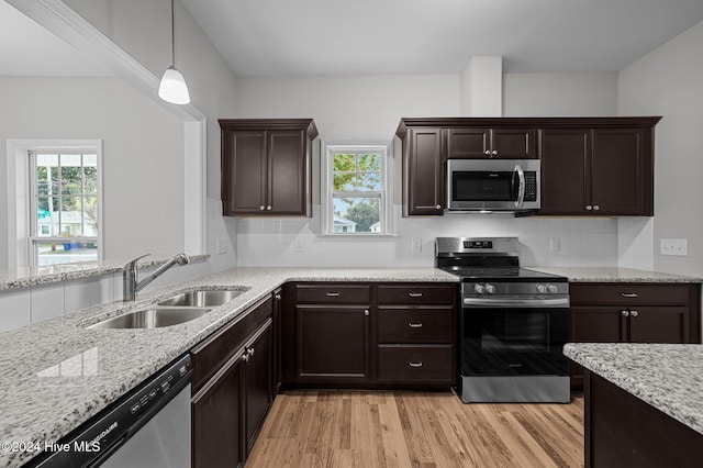 kitchen featuring stainless steel appliances, sink, tasteful backsplash, light hardwood / wood-style flooring, and decorative light fixtures