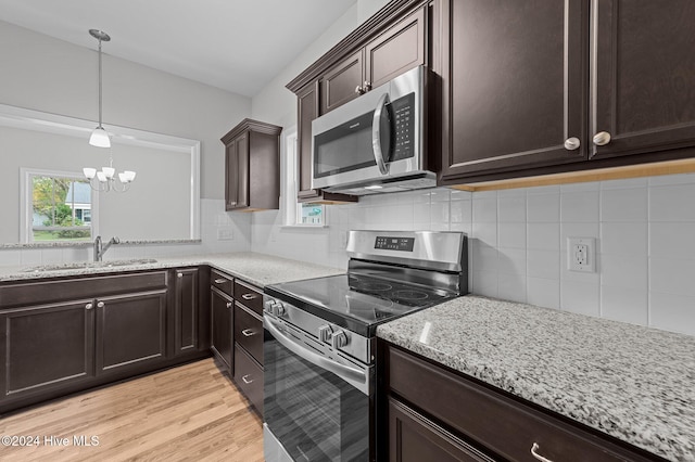 kitchen featuring stainless steel appliances, a notable chandelier, sink, tasteful backsplash, and light hardwood / wood-style flooring