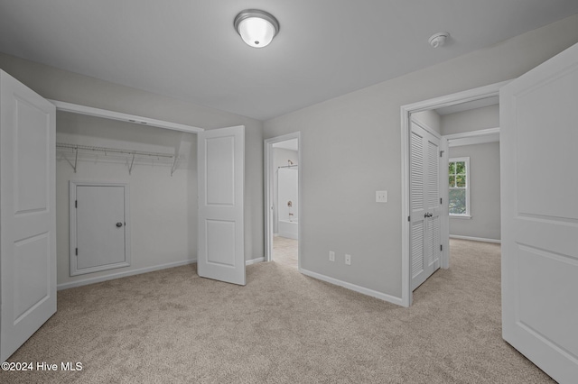 unfurnished bedroom with light colored carpet and a closet