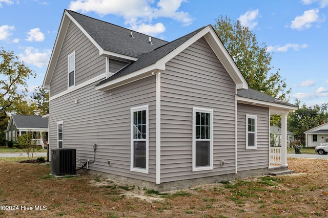 view of side of home with central AC and a lawn