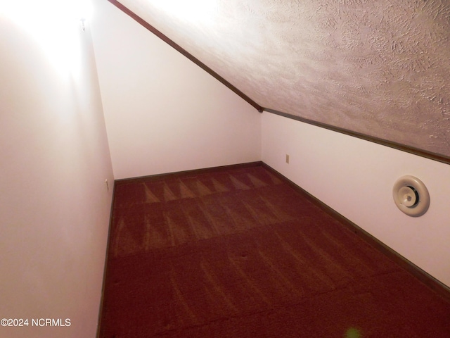 bonus room featuring a textured ceiling, dark colored carpet, and lofted ceiling