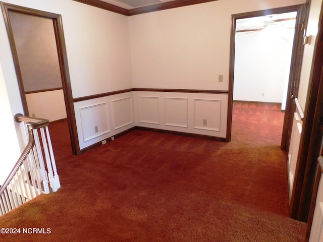 empty room featuring ceiling fan, dark colored carpet, and crown molding