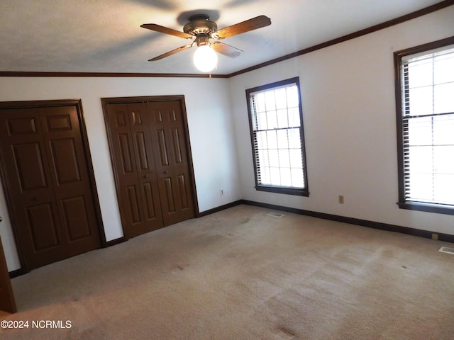 unfurnished bedroom with carpet flooring, multiple windows, and ceiling fan