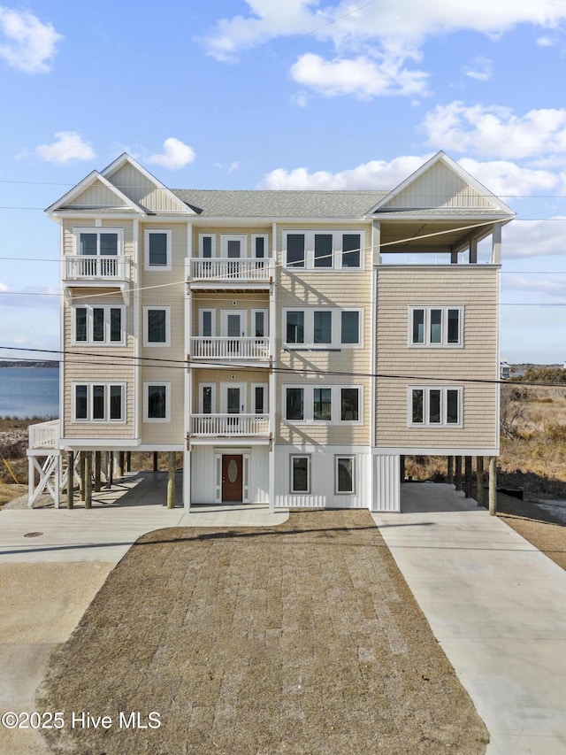 view of building exterior with a water view, a carport, and concrete driveway