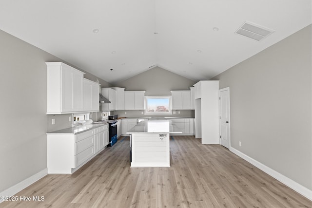 kitchen featuring range with electric stovetop, visible vents, white cabinets, light countertops, and a center island