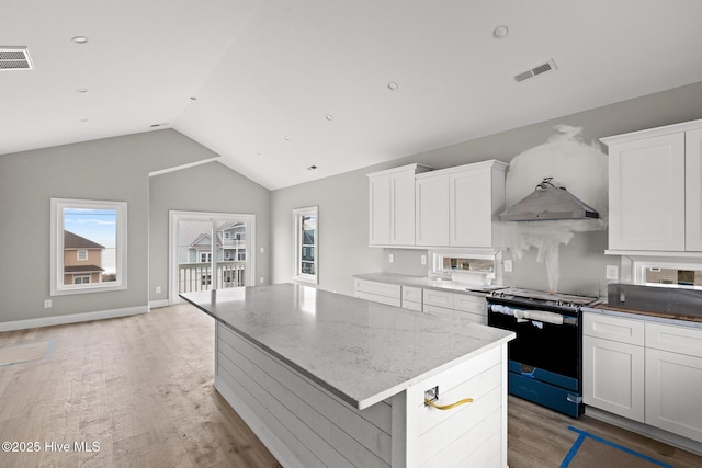 kitchen featuring under cabinet range hood, white cabinetry, a kitchen island, and range with electric cooktop