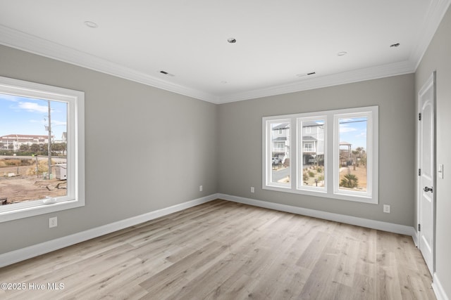 empty room featuring crown molding, light wood-type flooring, visible vents, and baseboards