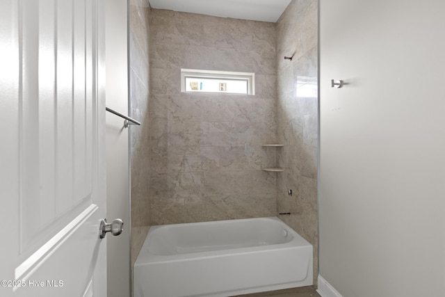 bathroom featuring bathing tub / shower combination and baseboards