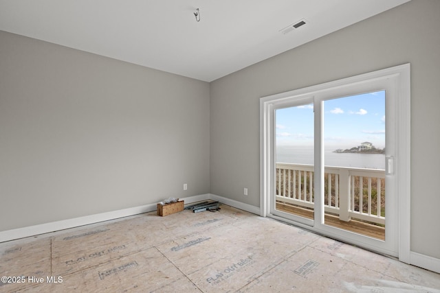 spare room featuring a water view, visible vents, and baseboards