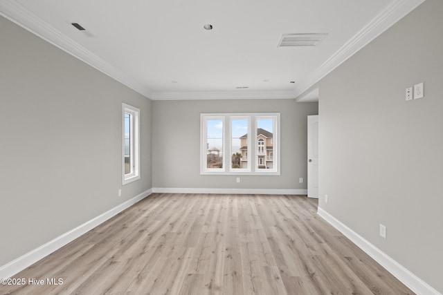 empty room featuring light wood finished floors, visible vents, baseboards, and ornamental molding