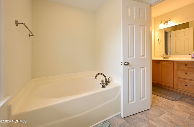 bathroom with vanity, hardwood / wood-style floors, and a tub to relax in