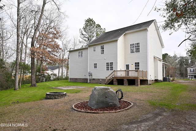 rear view of house with a deck, central air condition unit, a fire pit, and a lawn