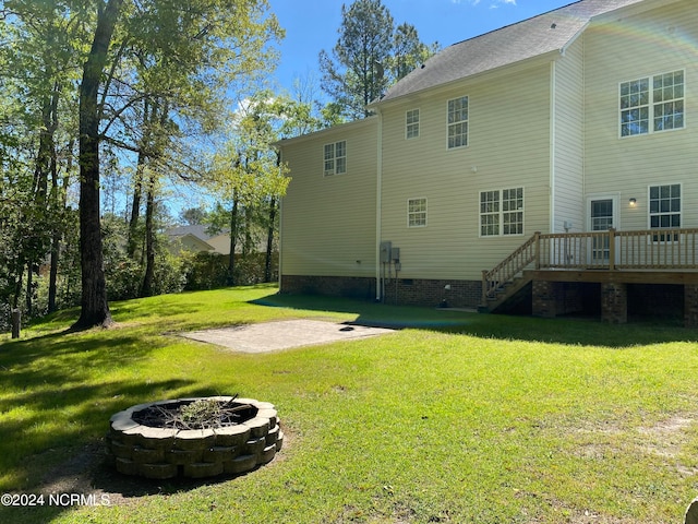 back of house featuring a yard, a fire pit, and a deck