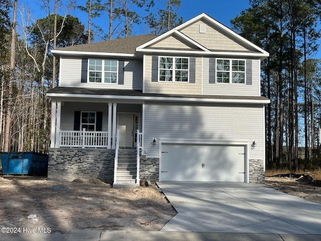 view of front of home with an attached garage, stone siding, a porch, and concrete driveway