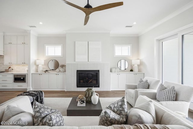 living room with crown molding, wood-type flooring, and a wealth of natural light