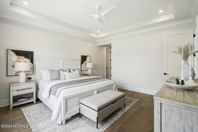 bedroom with ceiling fan, dark wood-type flooring, and a tray ceiling