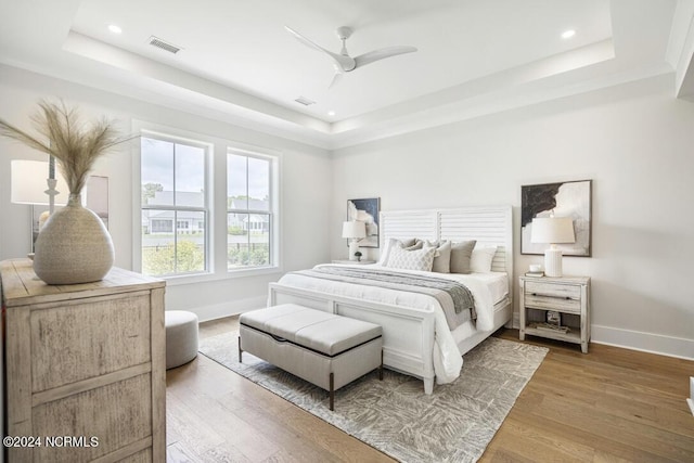 bedroom featuring wood-type flooring, ceiling fan, and a raised ceiling