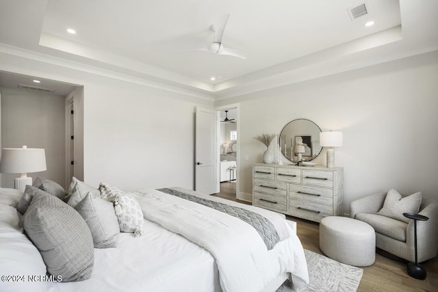 bedroom with ceiling fan, hardwood / wood-style flooring, and a tray ceiling