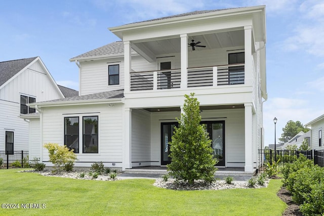 rear view of property with a balcony, a lawn, and ceiling fan