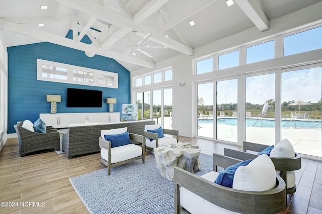 living room featuring high vaulted ceiling, beam ceiling, ceiling fan, and wooden walls