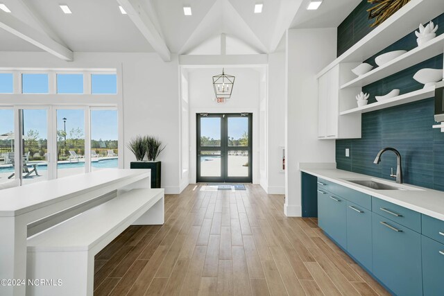 kitchen with blue cabinetry, sink, french doors, backsplash, and a healthy amount of sunlight