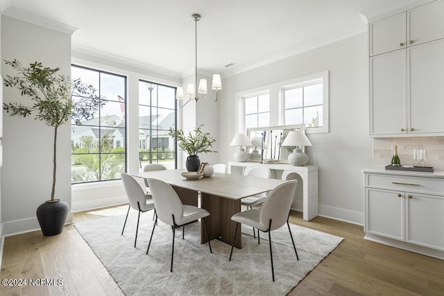 dining room with light hardwood / wood-style flooring, ornamental molding, and a chandelier