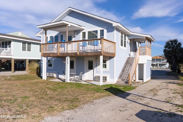 rear view of house with a balcony, a lawn, and a patio area