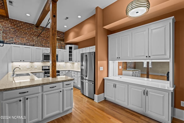 kitchen featuring sink, tasteful backsplash, white cabinetry, kitchen peninsula, and stainless steel appliances