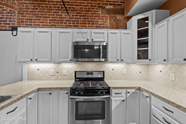 kitchen with backsplash, white cabinets, and stainless steel appliances