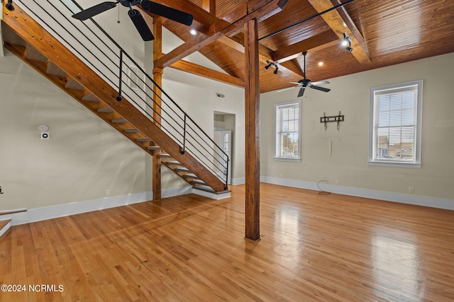 unfurnished living room featuring lofted ceiling with beams, light hardwood / wood-style floors, ceiling fan, and wooden ceiling