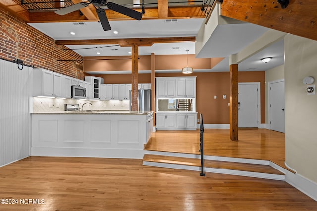 kitchen featuring kitchen peninsula, white cabinetry, brick wall, and appliances with stainless steel finishes