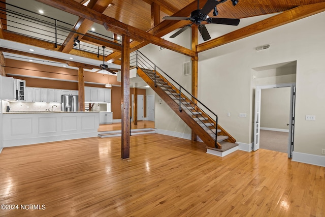 unfurnished living room with light hardwood / wood-style floors, high vaulted ceiling, and ceiling fan