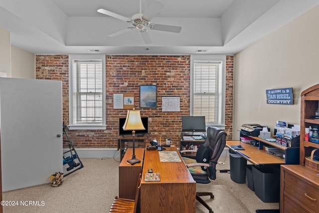 office with a raised ceiling, light carpet, plenty of natural light, and brick wall