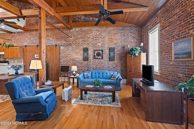 living room featuring beam ceiling, light hardwood / wood-style flooring, ceiling fan, and brick wall