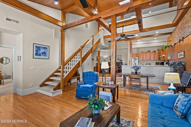 living room featuring beam ceiling, light wood-type flooring, high vaulted ceiling, and ceiling fan