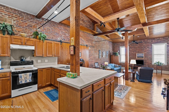 kitchen featuring a barn door, beamed ceiling, brick wall, white range, and light hardwood / wood-style floors