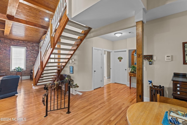 interior space featuring light hardwood / wood-style floors, wood ceiling, and brick wall